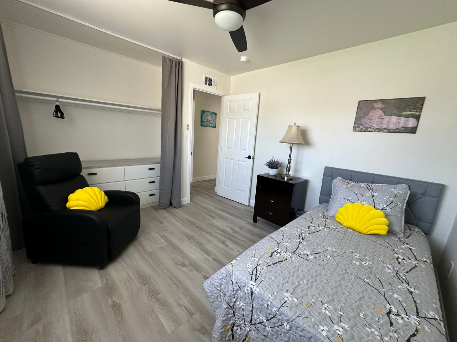 Private bedroom with gray blossom bedding, recliner and open closet