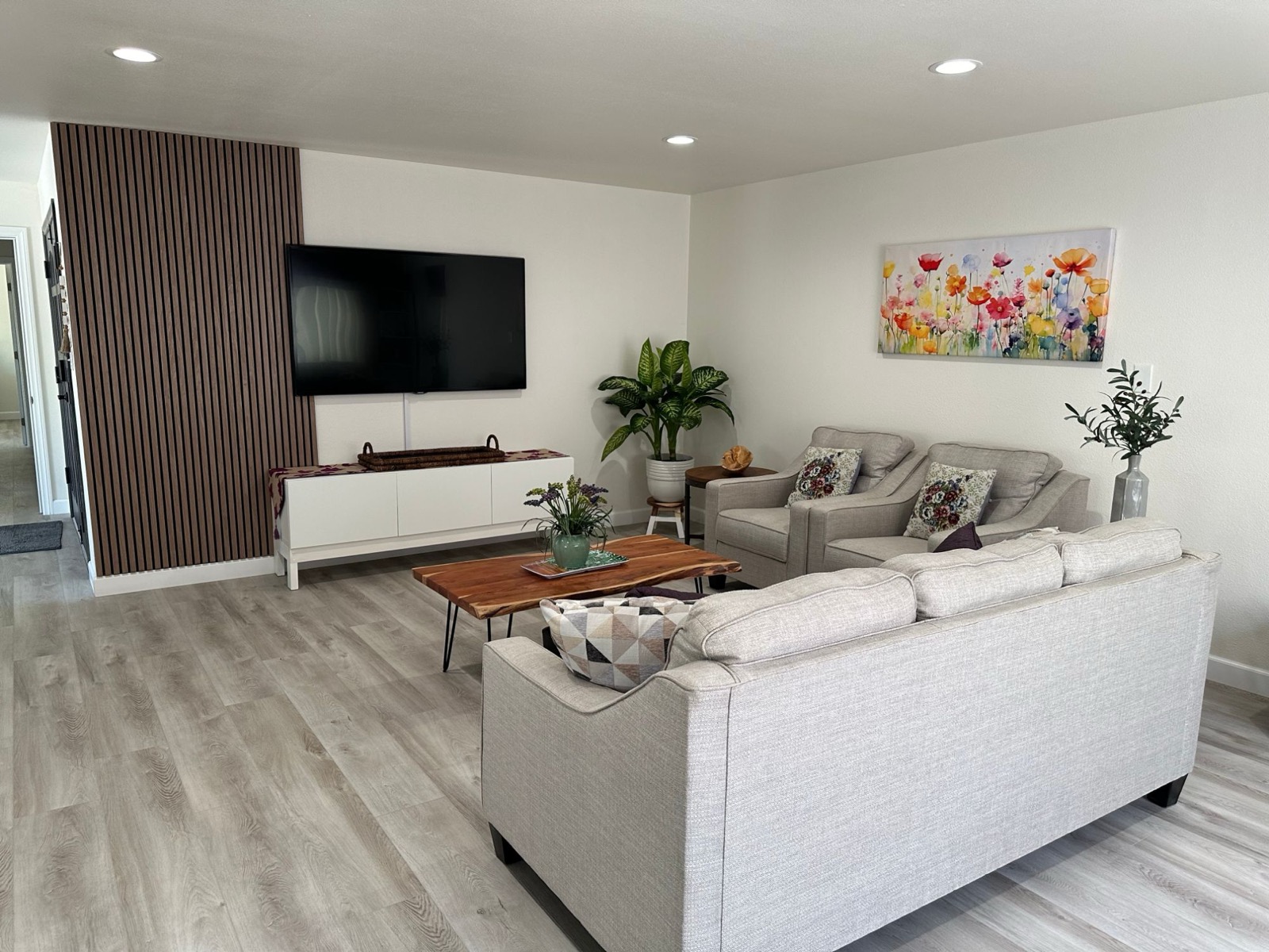 Living room with sofa, armchairs, coffee table and wall-mounted TV